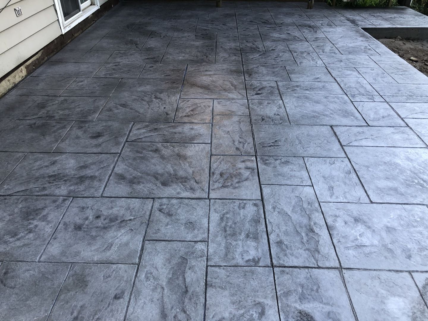 A gray concrete patio with a house in the background.