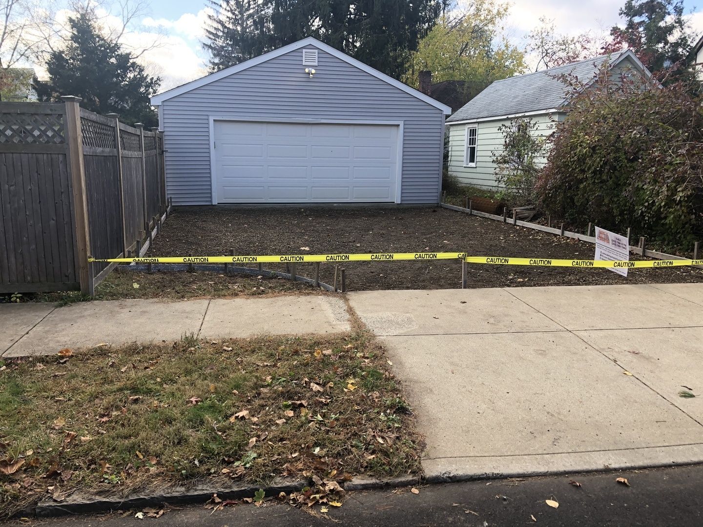 A garage with a yellow tape around it and a house in the background