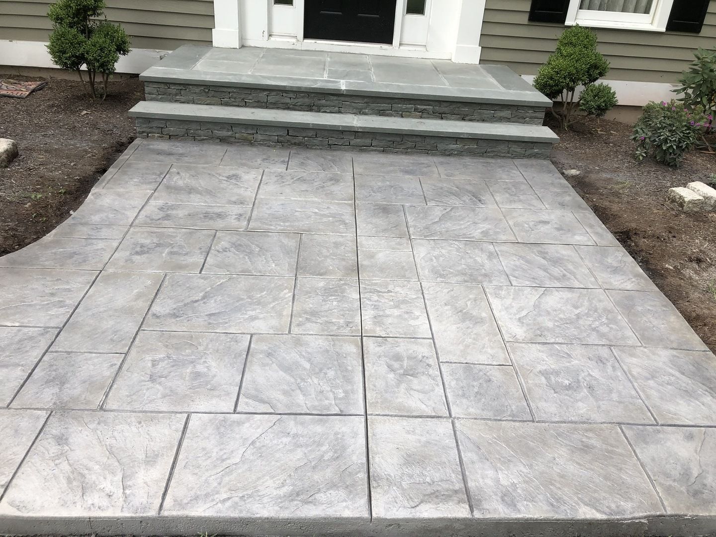 A concrete walkway with steps leading to the front door of a house.