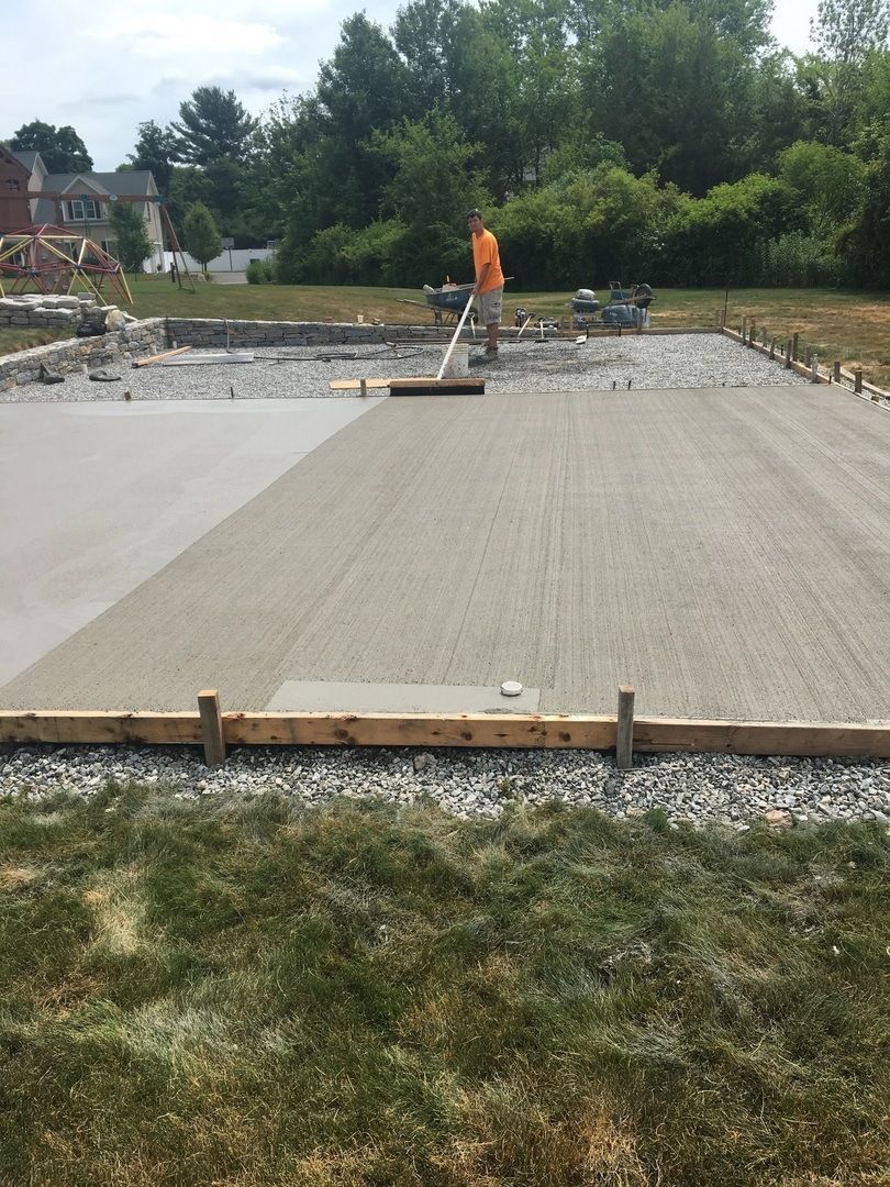 A man is spreading concrete on a construction site.