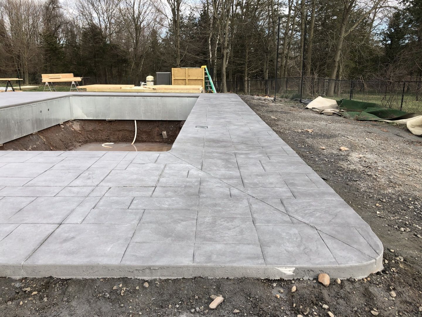 A concrete walkway is being built around a swimming pool.