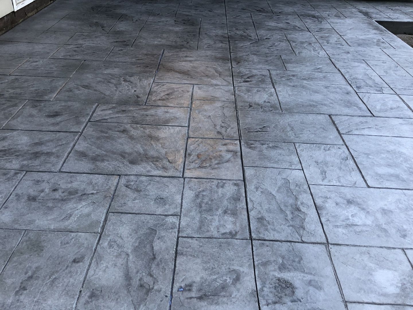 A close up of a concrete driveway with a brick pattern.