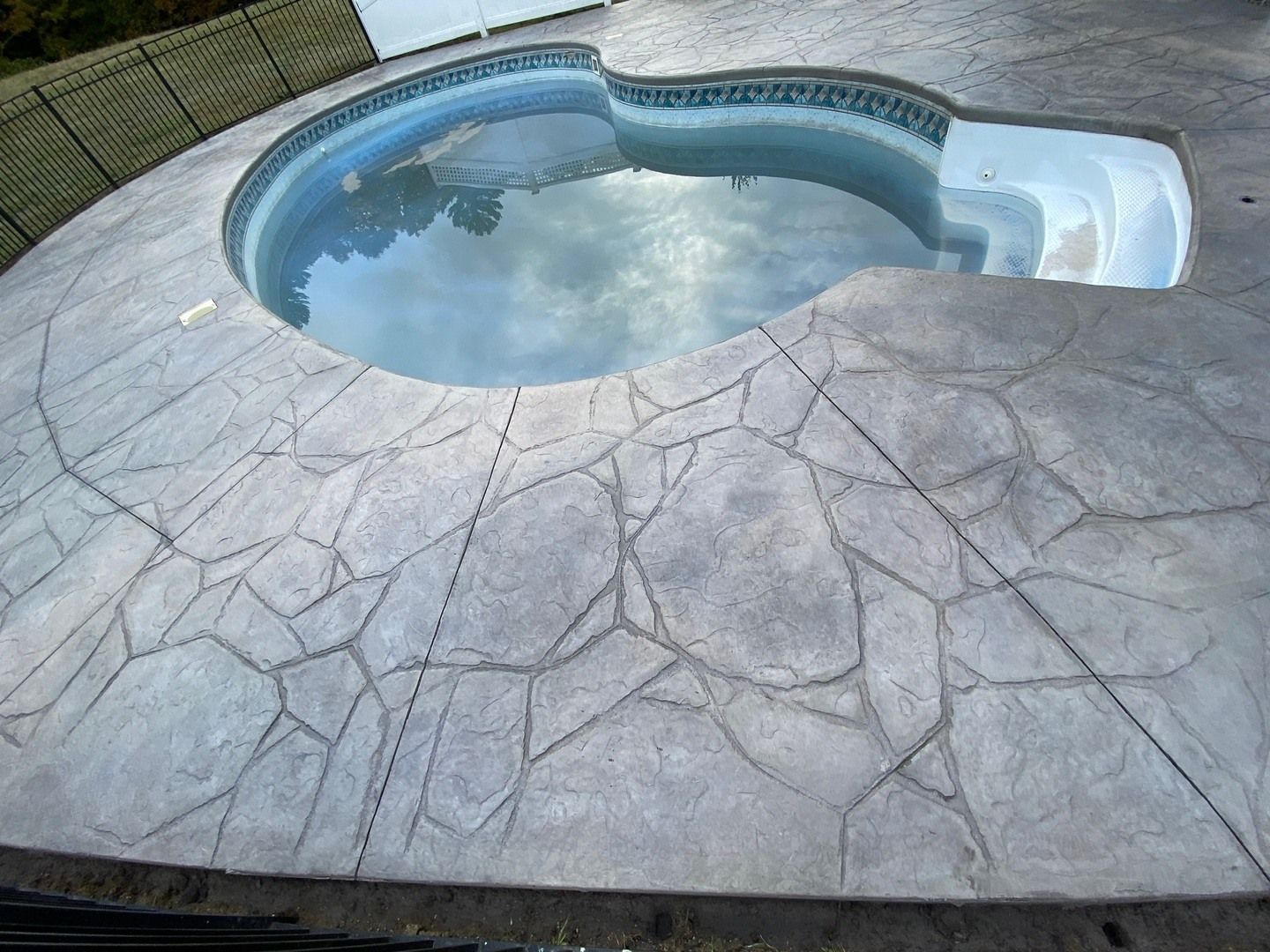 A swimming pool is surrounded by a stone deck