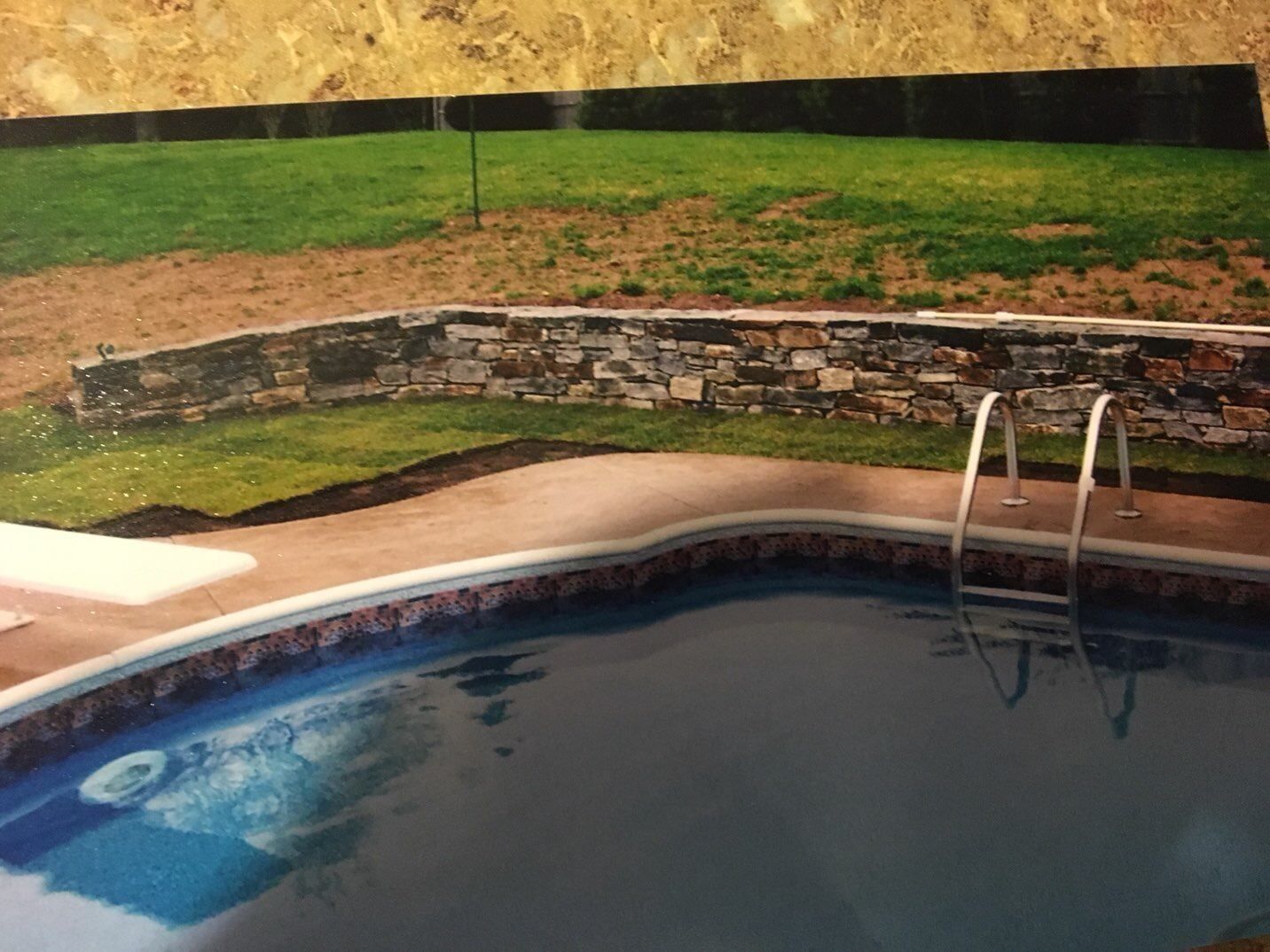 A picture of a swimming pool with a stone wall in the background