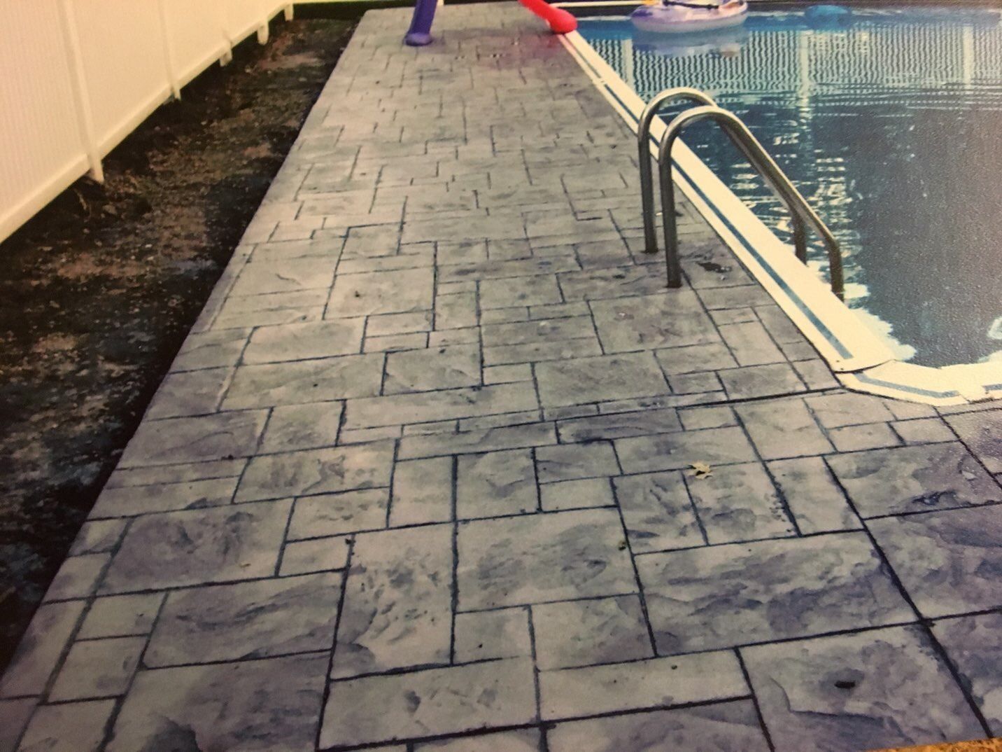 A concrete walkway leading to a swimming pool