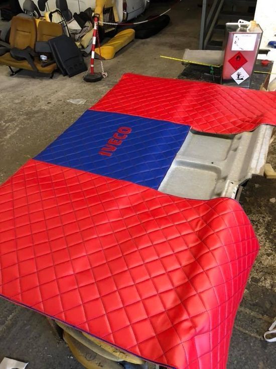 Una coperta trapuntata rossa e blu con la scritta Iveco sopra