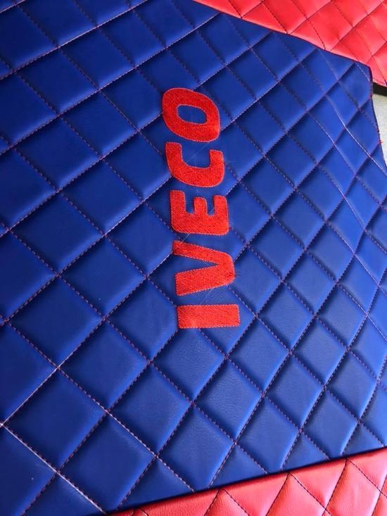 Un tappetino trapuntato blu e rosso con la scritta Iveco sopra