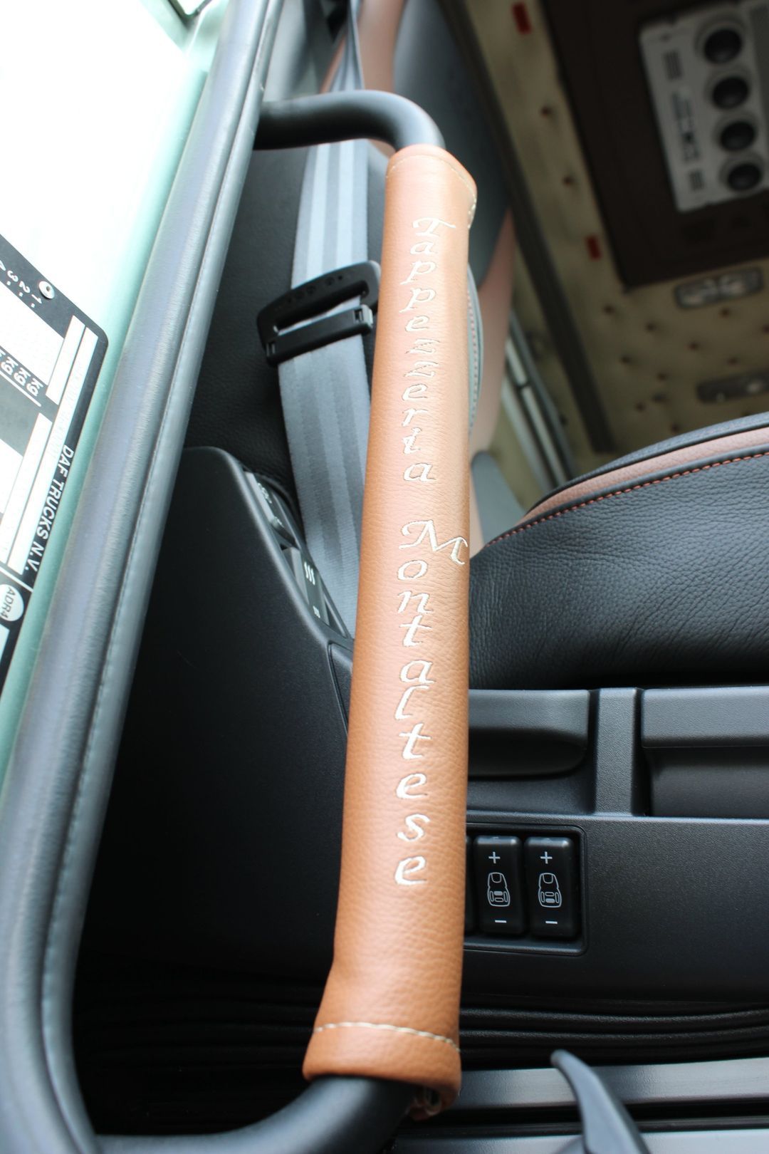 Un primo piano di una maniglia in pelle marrone di un'auto