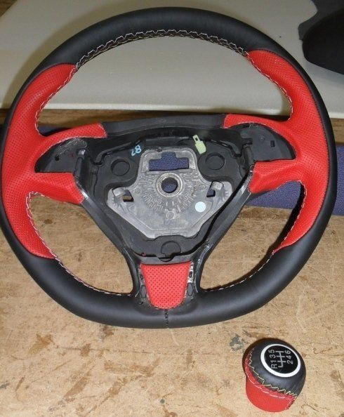 Un volante nero e rosso accanto a una leva del cambio