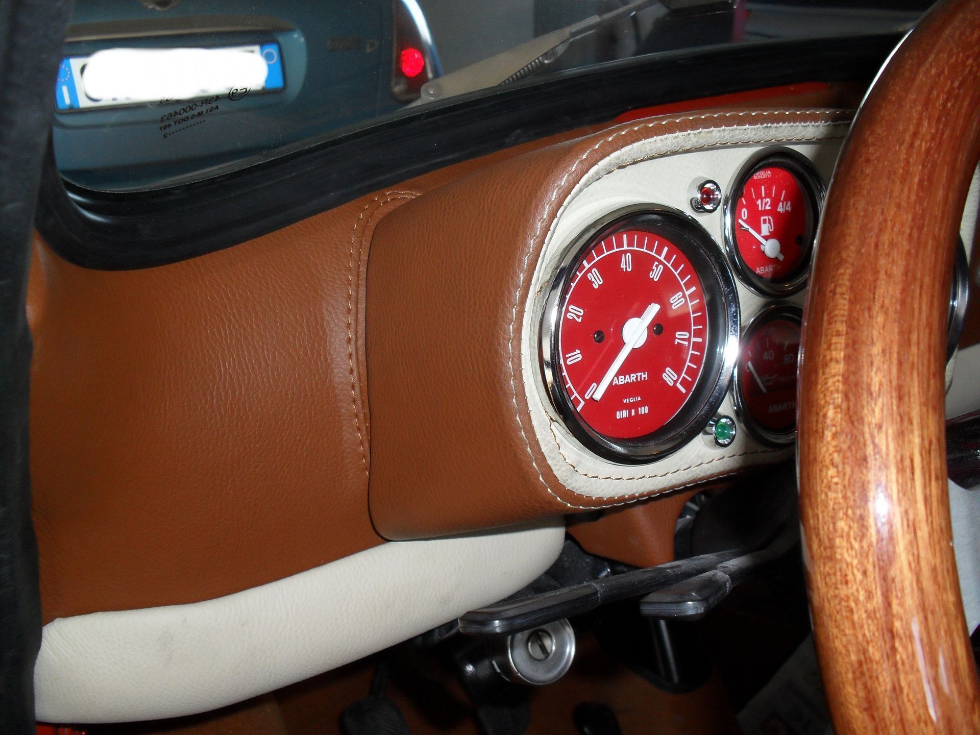 Un cruscotto di un'auto con un indicatore rosso e un volante di legno