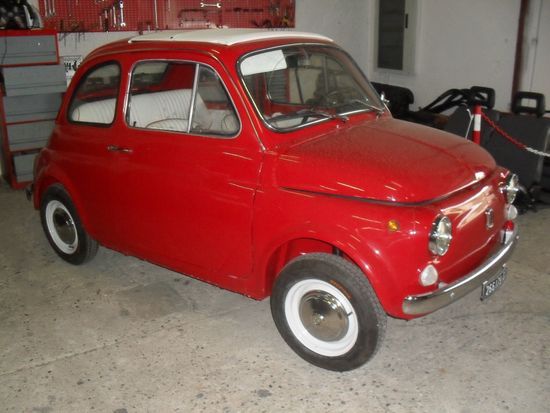 Un'auto rossa con gomme bianche è parcheggiata in un garage