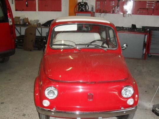 Un'auto rossa con la capote bianca è parcheggiata in un garage