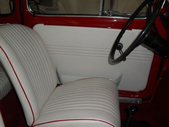 Un'auto rossa con sedili bianchi e un volante