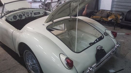 Un'auto sportiva bianca con il cofano aperto è parcheggiata in un garage.