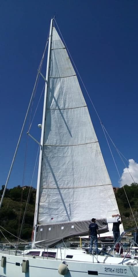 Una barca a vela con una grande vela è ormeggiata in acqua.