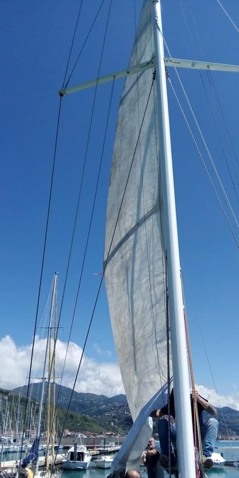 Un uomo è in piedi su una barca a vela con una grande vela.