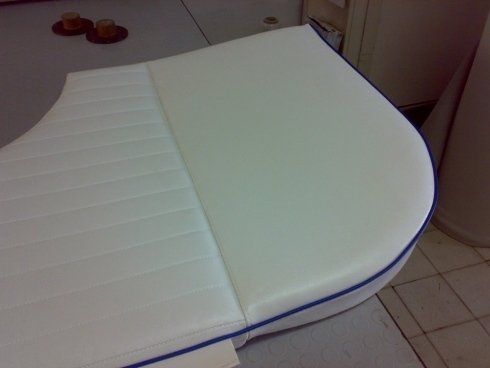 Un cuscino bianco con una rifinitura blu è appoggiato su un pavimento piastrellato