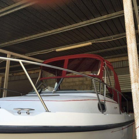 Una barca bianca con un baldacchino rosso è in un garage