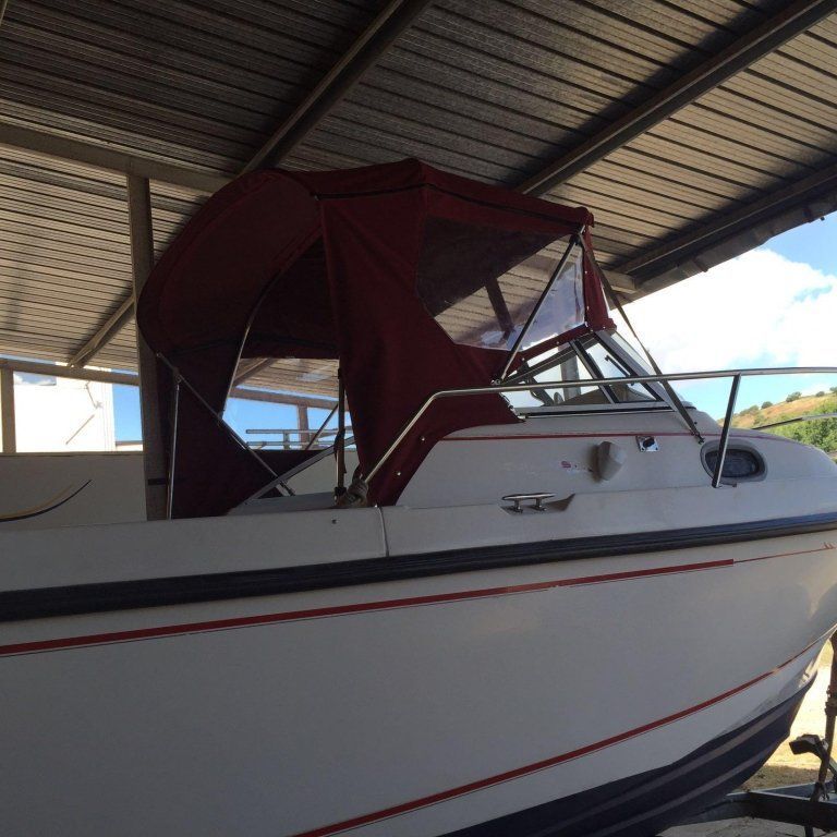 Una barca bianca con un baldacchino rosso è sotto un tetto