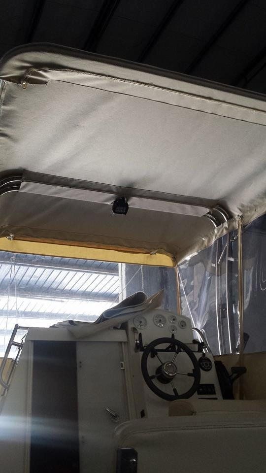 Una barca con tendalino e volante è parcheggiata in un garage.