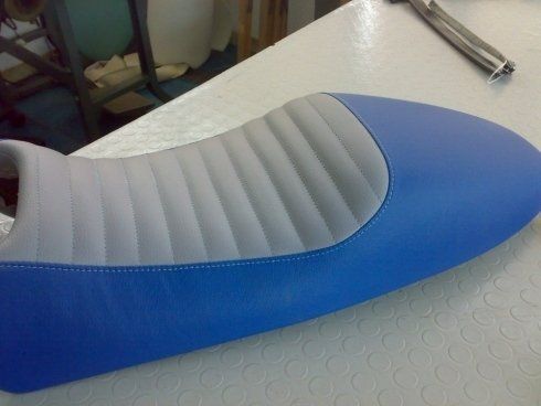 Un sedile da motocicletta blu e grigio è appoggiato su un tavolo