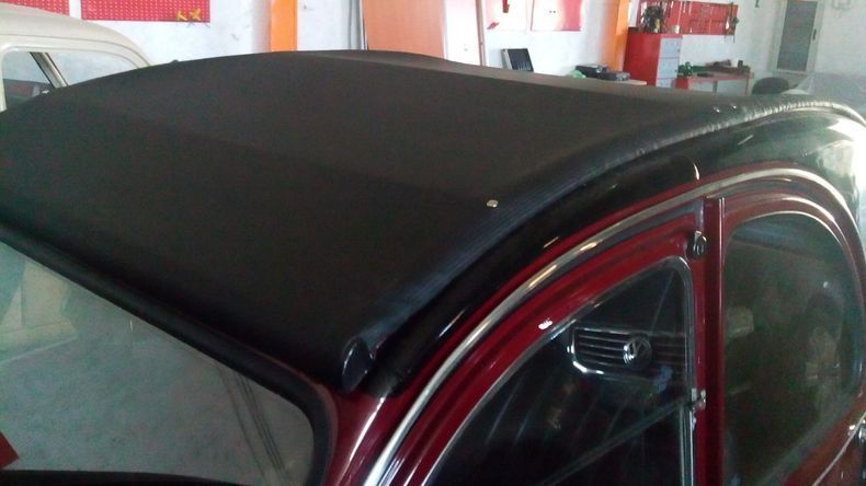 Un'auto rossa con il tetto nero è parcheggiata in un garage
