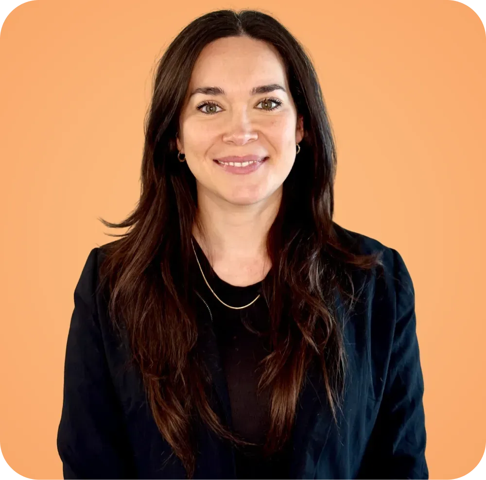 A woman in a black jacket and necklace is smiling for the camera.