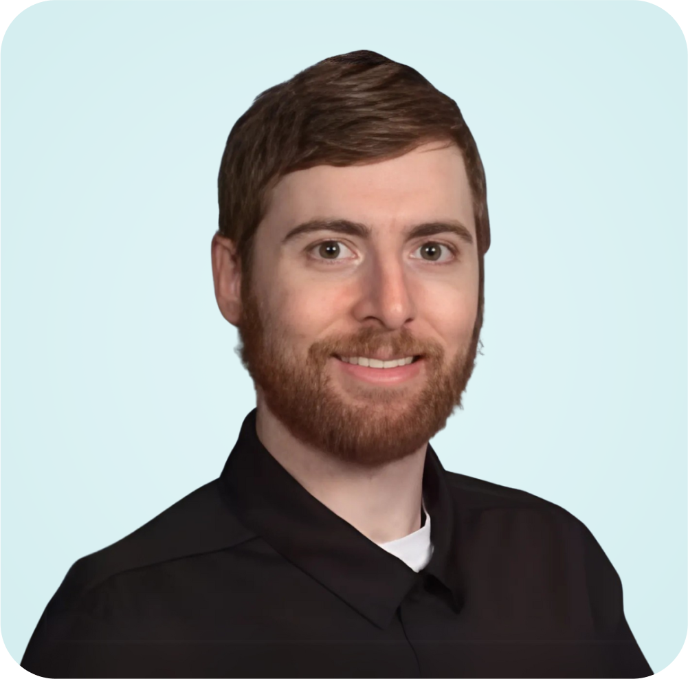 A man with a beard is wearing a black shirt and smiling.