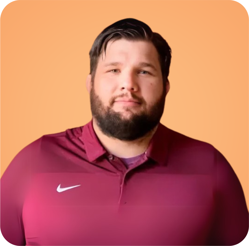 A man with a beard is wearing a maroon nike shirt.