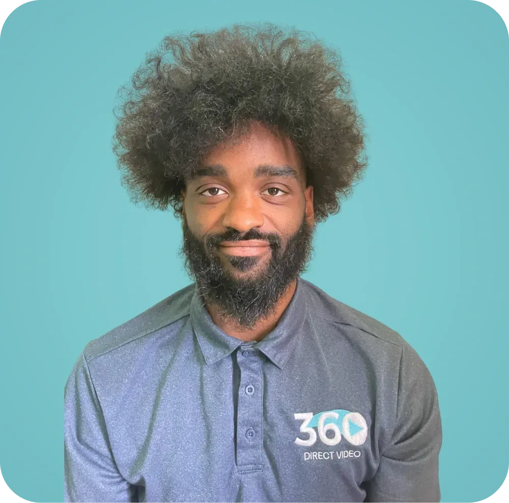 A man with curly hair and a beard is wearing a blue polo shirt.