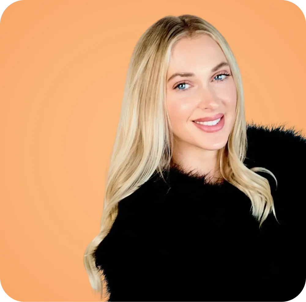 A woman with blonde hair is wearing a black sweater and smiling.