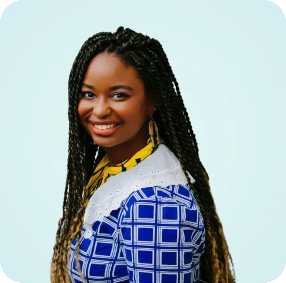 A woman with braids is smiling and wearing a blue and white shirt