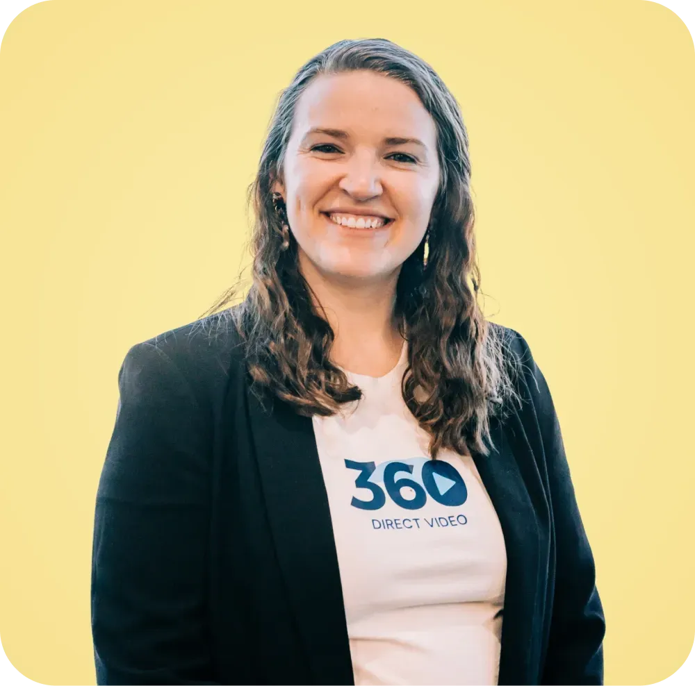 A woman wearing a 360 t-shirt and a black jacket is smiling.