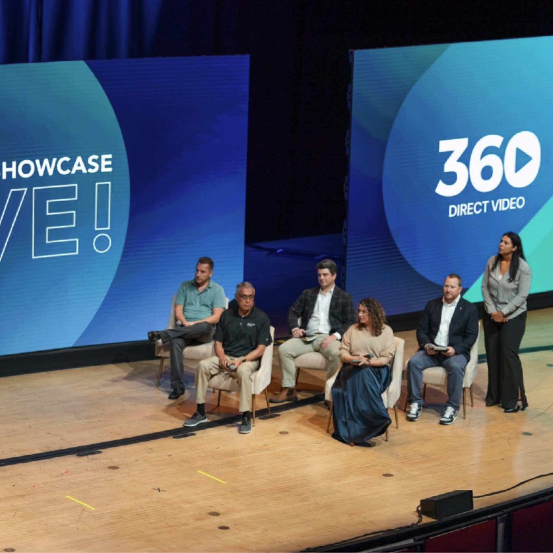 A group of people sitting on a stage with a sign that says 360 direct video