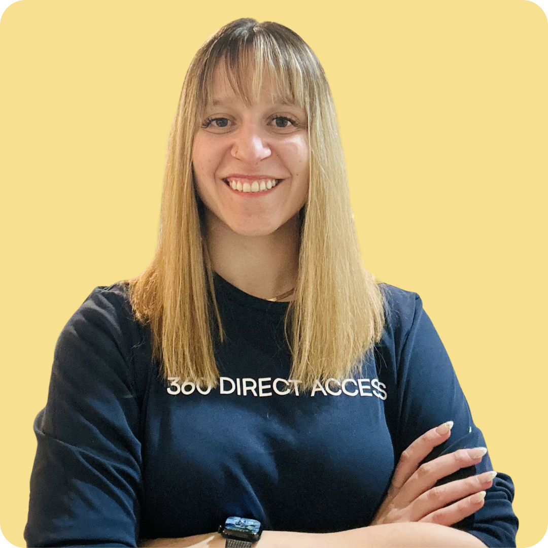 A woman in a dark blue shirt is standing with her arms crossed and smiling.