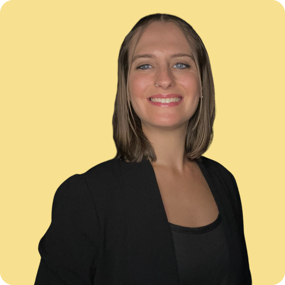 Yellow background with Becca smiling to the camera. She is wearing a black shirt and black blazer.