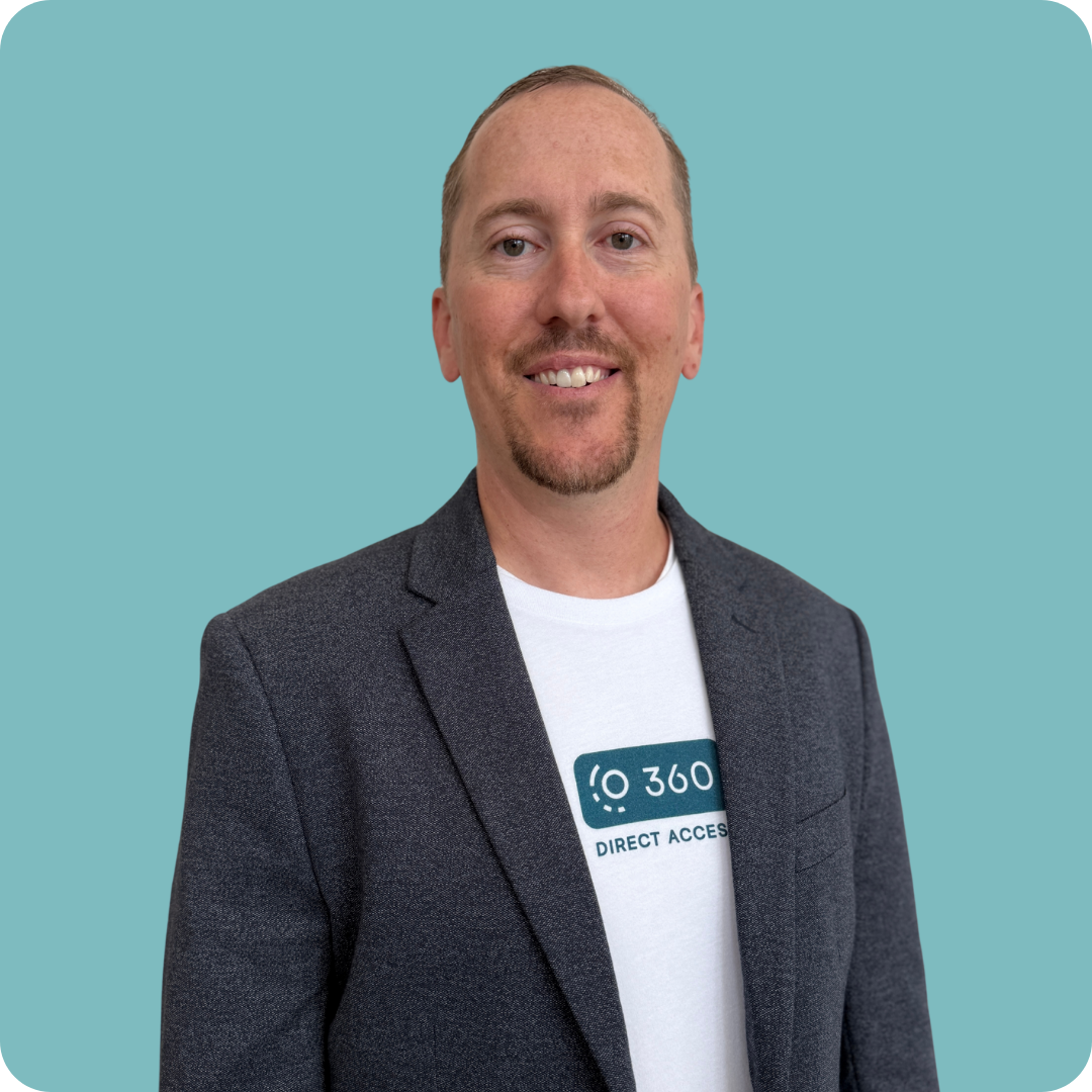 A man in a suit and a t-shirt with the word 360 on it is standing in front of a blue background.