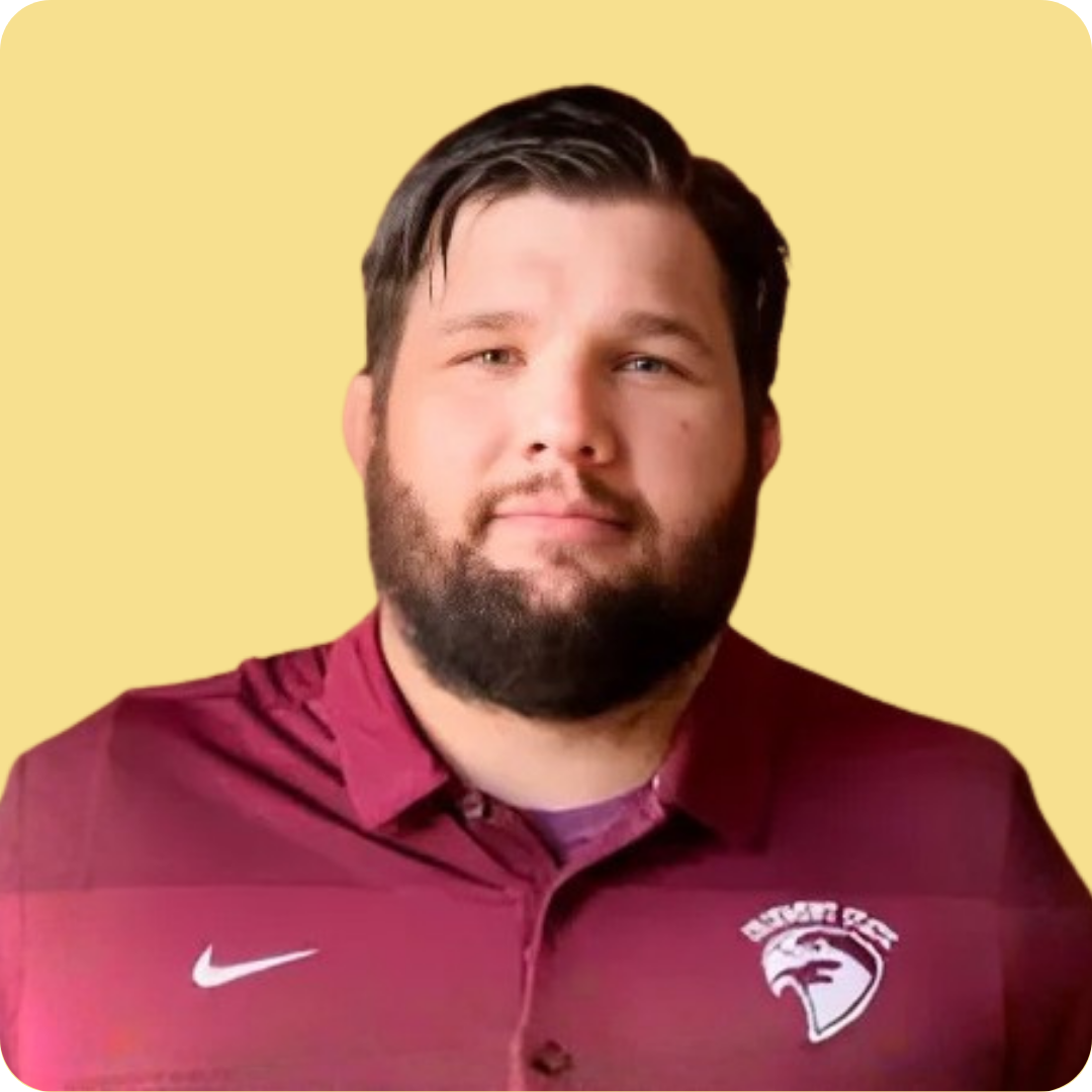 A man with a beard is wearing a maroon nike shirt.