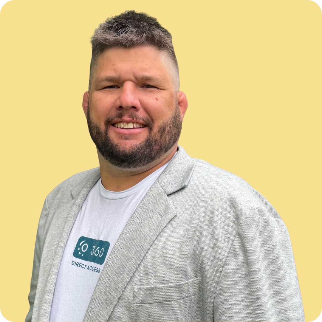 A man with a beard is wearing a white 360 shirt with light grey blazer.