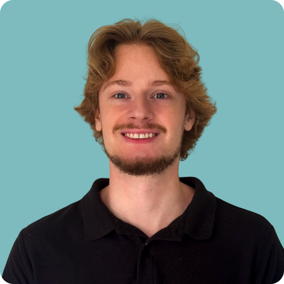 A man with a beard is wearing a black shirt and smiling.