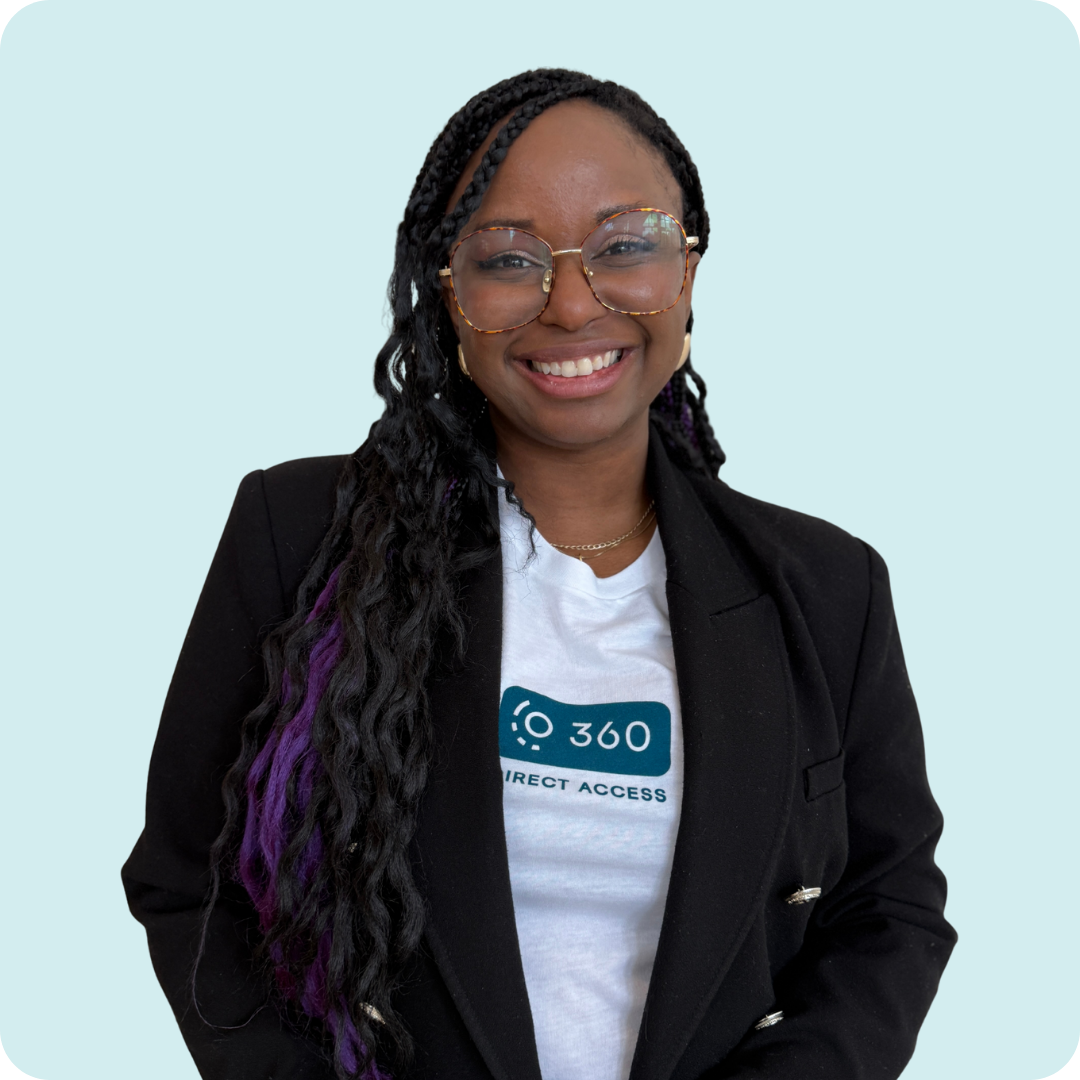 A woman with braids is smiling and wearing a white 360 shirt with a black blazer.