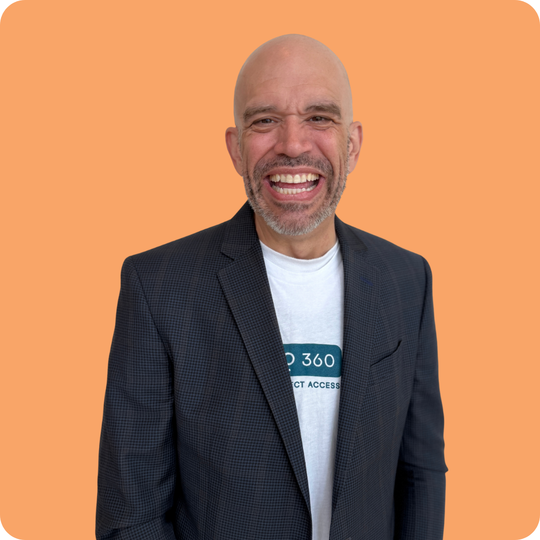 A bald man with a beard is smiling and wearing a black shirt.