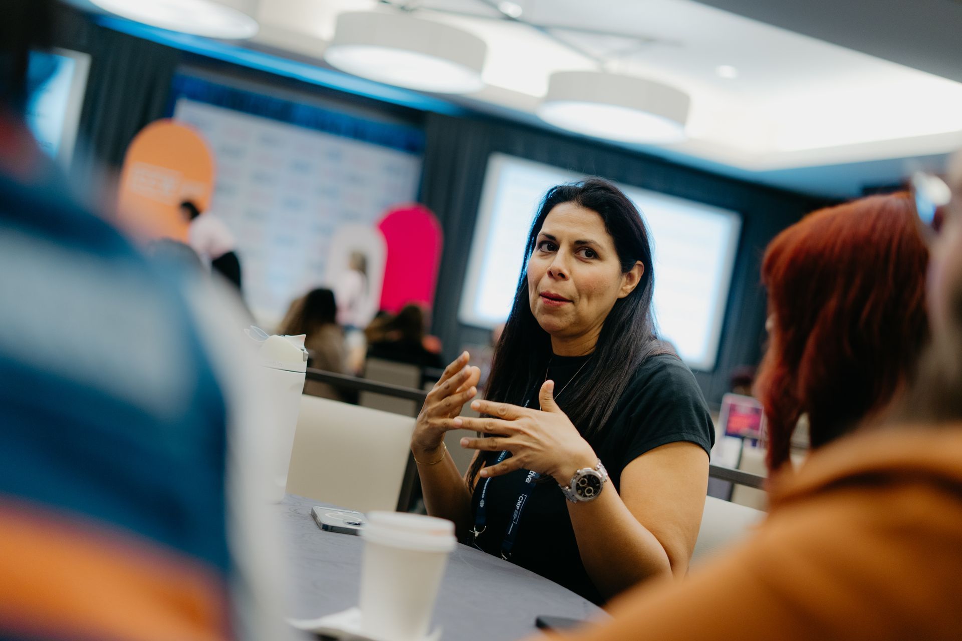 Vannessa is wearing a black shirt and seated at a table with other people.