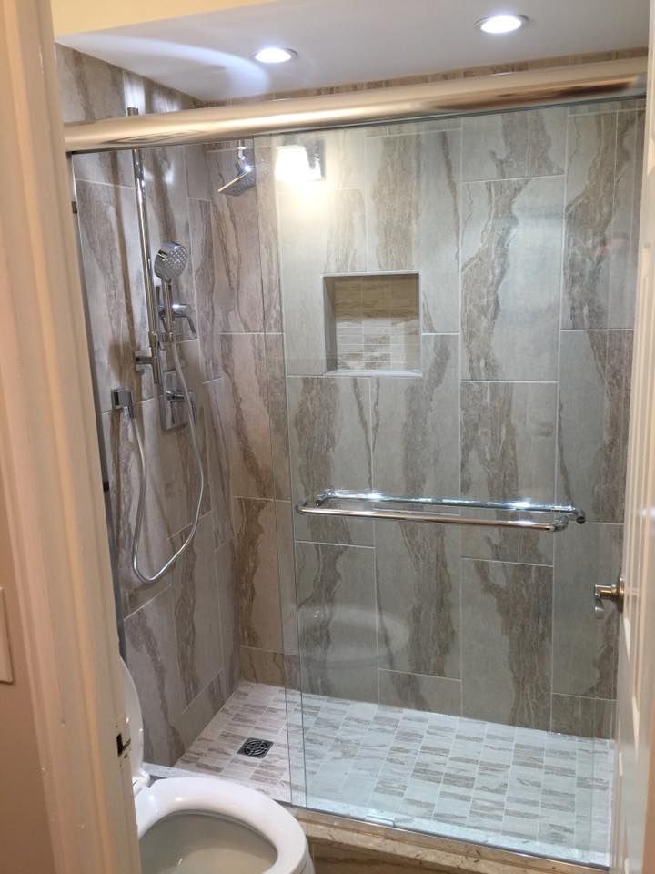 A bathroom with a toilet and a shower with a sliding glass door.