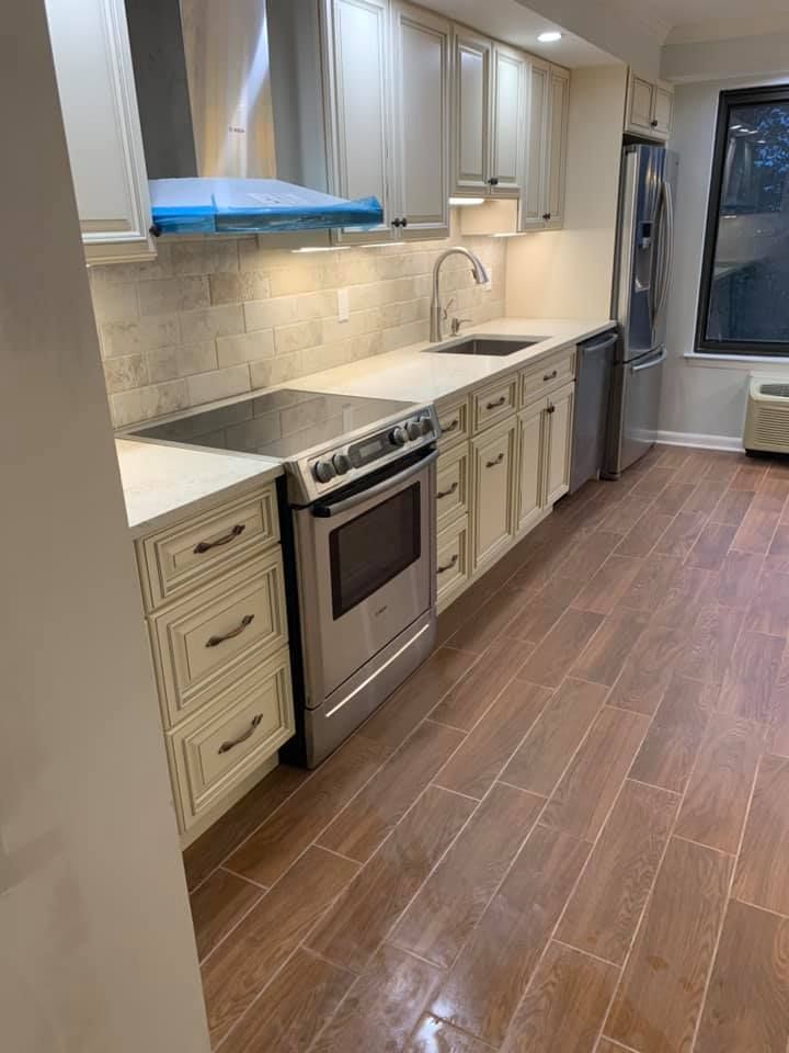 A kitchen with white cabinets , stainless steel appliances , a sink , and a refrigerator.