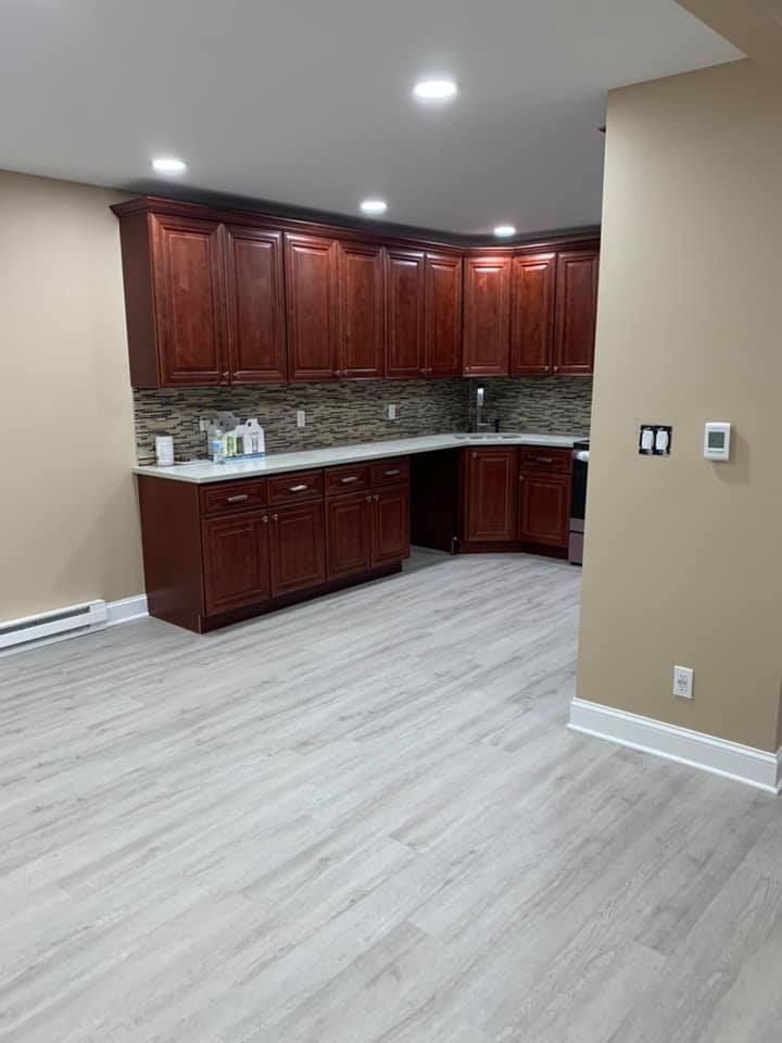 A kitchen with wooden cabinets and white counter tops in a basement.