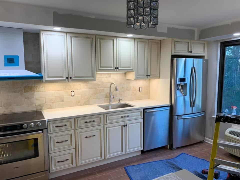 A kitchen with white cabinets , stainless steel appliances , a sink , refrigerator and dishwasher.
