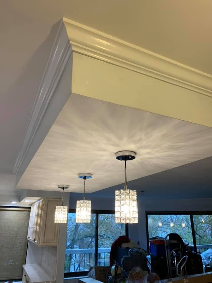 A kitchen with a crown molding and pendant lights on the ceiling.