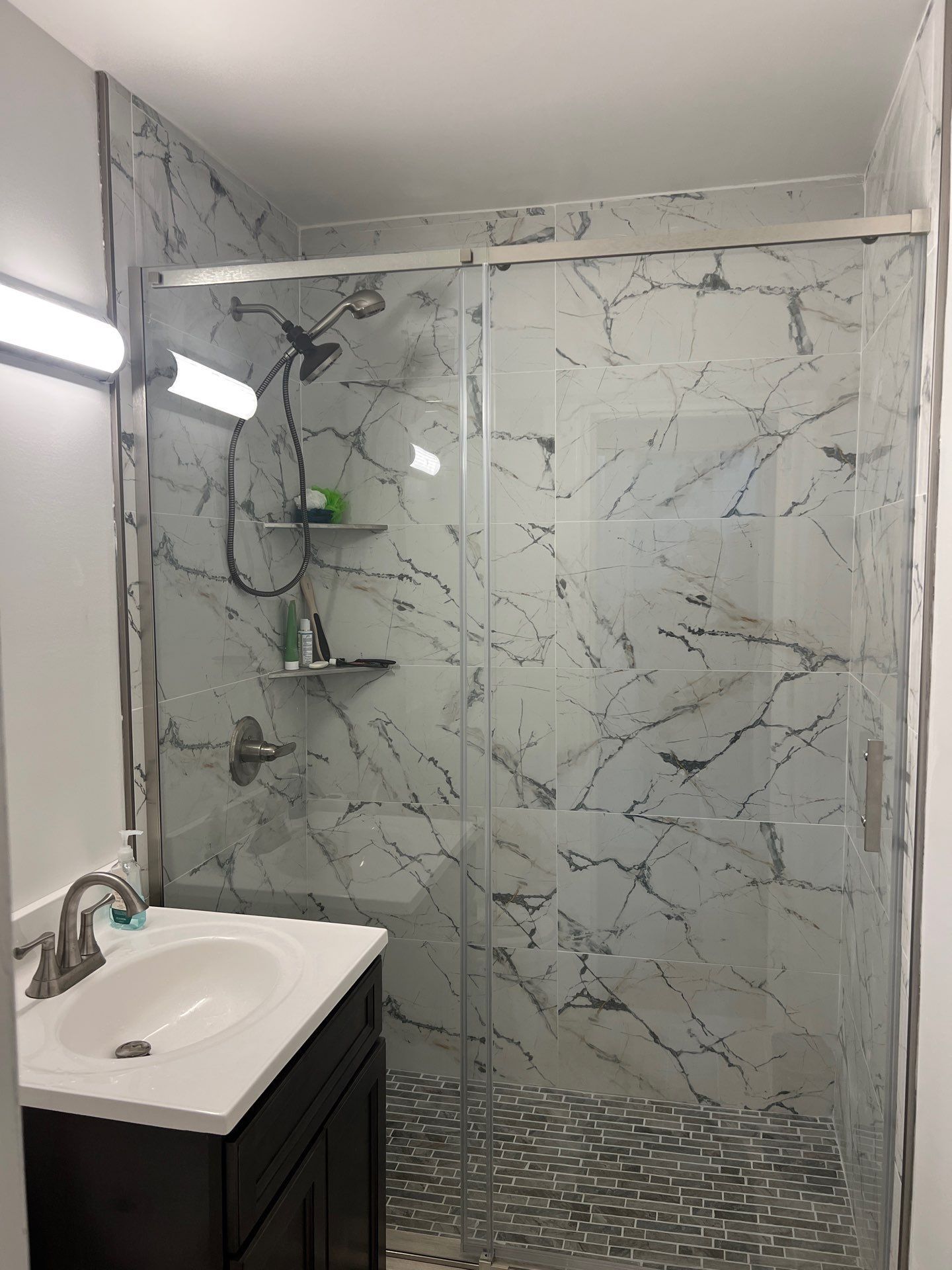 A bathroom with a sink and a walk in shower.