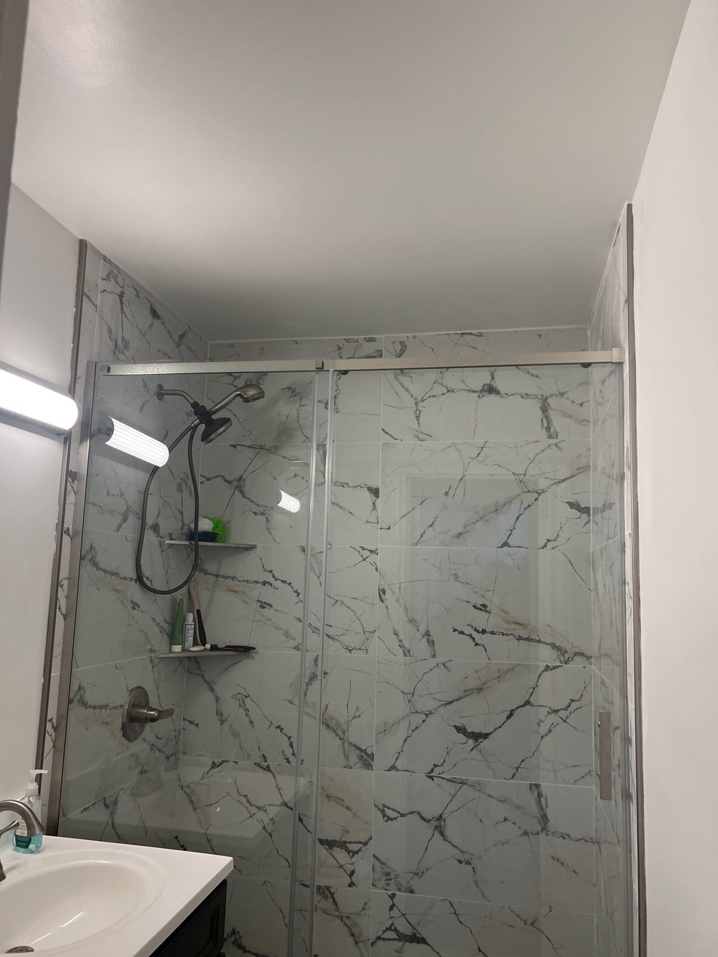 A bathroom with marble tiles and a sliding glass shower door.